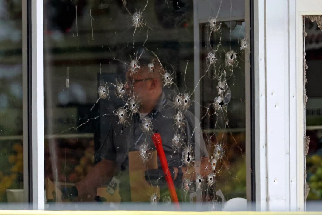 Se puede ver el daño en una ventana frontal mientras los oficiales de la ley trabajan en la escena del tiroteo en la tienda Mad Butcher en Fordyce, Arkansas, el 21 de junio de 2024. (Colin Murphey/Arkansas Democrat-Gazette a través de AP)