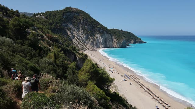 GRECIA: Bañistas bajan hacia la playa de Milos, en la isla de Lefkada, el 11 de julio de 2025, cerca de Agios Nikitas, Grecia. Lefkada, una isla situada en la costa occidental de Grecia, en el mar Jónico, es un popular destino turístico de verano conocido por sus playas vírgenes. (Foto de Sean Gallup/Getty Images)