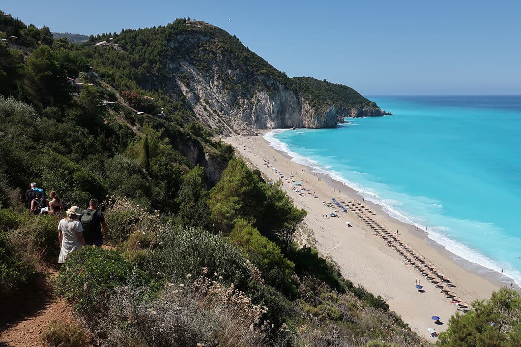 GRECIA: Bañistas bajan hacia la playa de Milos, en la isla de Lefkada, el 11 de julio de 2025, cerca de Agios Nikitas, Grecia. Lefkada, una isla situada en la costa occidental de Grecia, en el mar Jónico, es un popular destino turístico de verano conocido por sus playas vírgenes. (Foto de Sean Gallup/Getty Images)