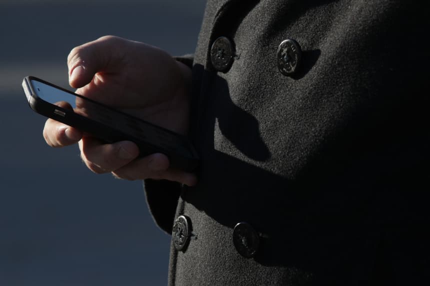 Un hombre revisa su teléfono celular mientras espera en la fila para entrar a la Corte Suprema de Estados Unidos y presenciar una audiencia el 29 de noviembre de 2017 en Washington, DC.(Alex Wong/Getty Images)