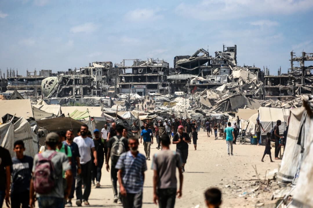 Palestinos caminan por una calle cerca de edificios dañados por la guerra en la ciudad de Gaza el 8 de agosto de 2025. (Bashar Taleb/AFP vía Getty Images)

