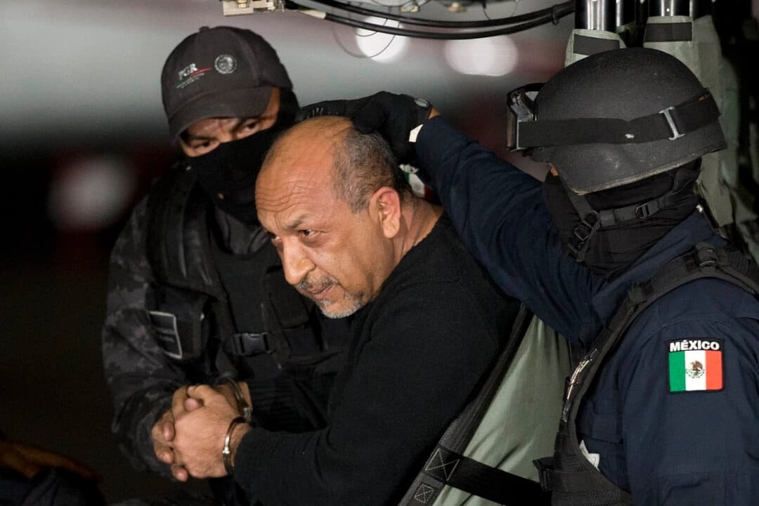 La policía federal mexicana escolta a quien identifican como Servando "La Tuta" Gomez, líder del cártel de los Caballeros Templarios, mientras se encuentra sentado dentro de un helicóptero en un hangar federal en Ciudad de México el 27 de febrero de 2015. (Eduardo Verdugo/AP Photo)
