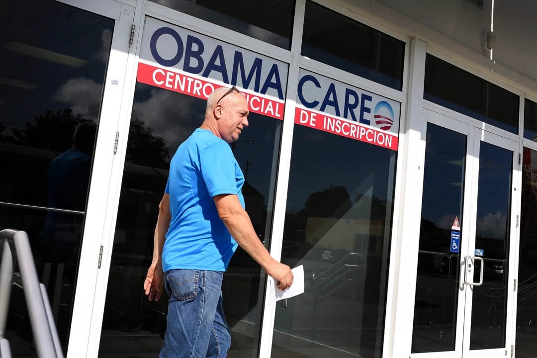 Un hombre camina frente a una oficina con un cartel de Obamacare en Miami, Florida, en una fotografía de archivo. (Joe Raedle/Getty Images).