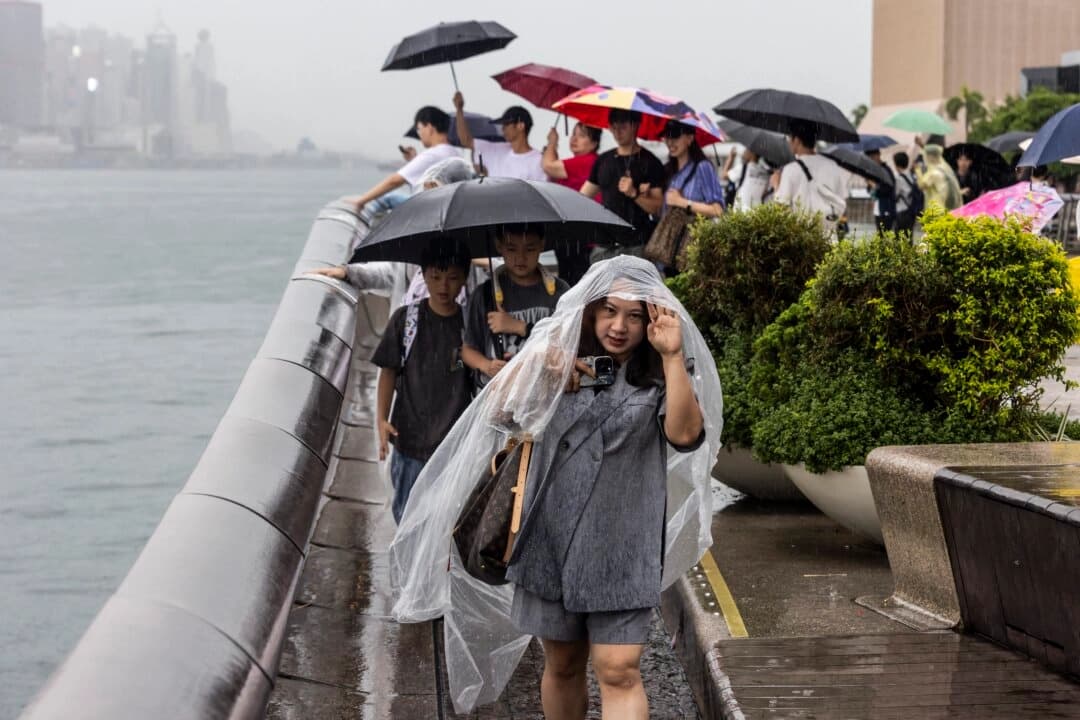 La gente utiliza paraguas para protegerse de la lluvia mientras el tifón Podul se debilita y se convierte en una tormenta tropical severa, en Hong Kong, el 14 de agosto de 2025. (Isaac Lawrence /AFP a través de Getty Images).