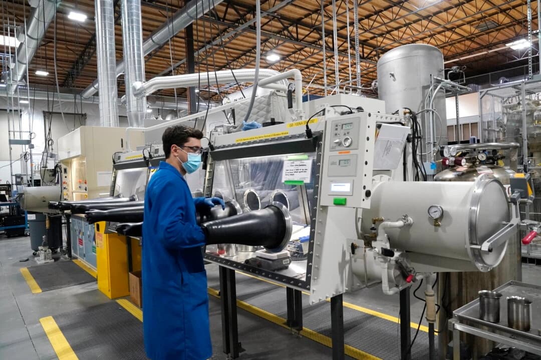 El ingeniero de pruebas Jacob Wilcox saca el brazo de una caja de guantes utilizada para procesar sodio en TerraPower, una empresa que desarrolla y construye pequeños reactores nucleares en Everett, Washington, el 13 de enero de 2022. (Elaine Thompson/AP Photo)