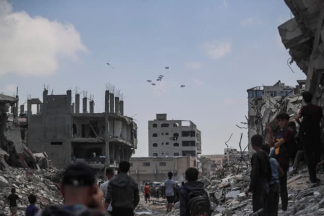 Palestinos observan paquetes de ayuda lanzados desde el aire sobre Gaza, en la ciudad de Gaza, el 8 de agosto de 2025. (Mahmoud Issa/Reuters)