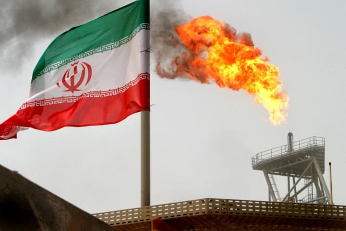 Una llamarada de gas en una plataforma petrolera junto a una bandera iraní en el Golfo Pérsico, el 25 de julio de 2005. (Raheb Homavandi/Reuters)