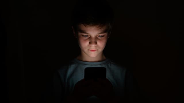 En esta ilustración fotográfica, un adolescente mira la pantalla de un teléfono móvil el 17 de enero de 2023 en Londres, Inglaterra. (Leon Neal/Getty Images)