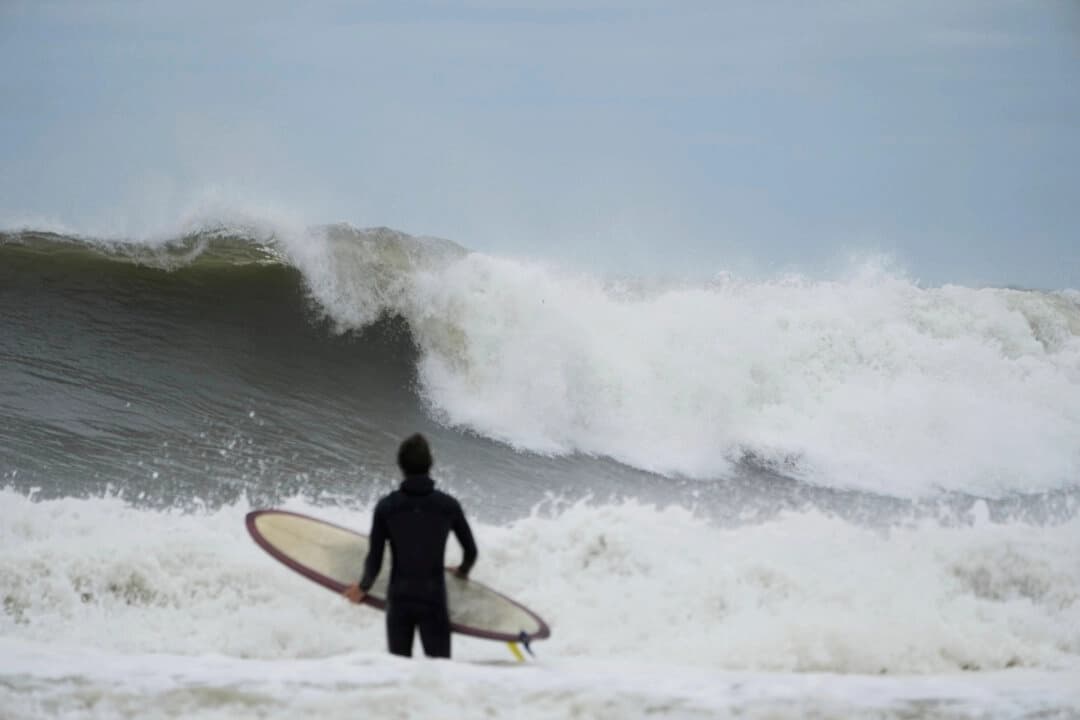 Un surfista intenta meterse al agua, pasando por grandes olas impulsadas por el huracán Erin, en Rockaway Beach, en el distrito de Queens, Nueva York, el 21 de agosto de 2025. (Seth Wenig/AP Photo)