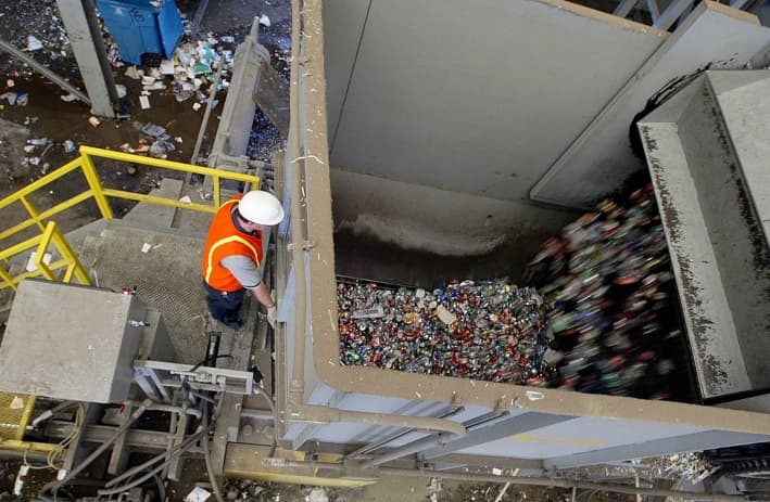 Un trabajador observa cómo se vacían los materiales reciclables en un contenedor en la planta de reciclaje de Norcal Waste, en San Francisco, el 11 de julio de 2003. (Justin Sullivan/Getty Images)