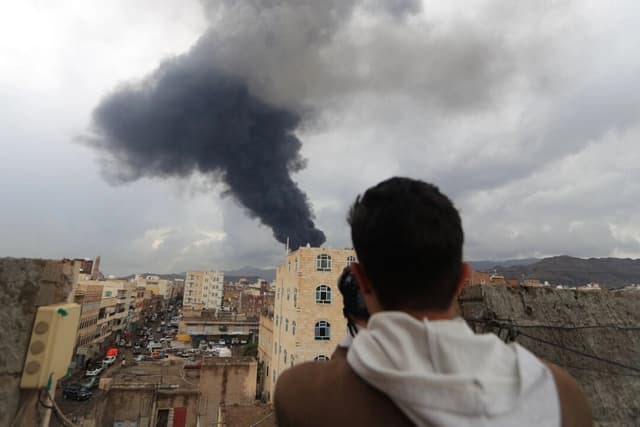 Un fotoperiodista toma una foto del humo tras un ataque aéreo israelí sobre Saná, la capital yemení controlada por los hutíes, el 24 de agosto de 2025. El ejército israelí afirmó que los objetivos eran instalaciones militares, incluidas zonas cercanas al palacio presidencial, centrales eléctricas y un depósito de combustible. (Mohammed Huwais/AFP a través de Getty Images)
