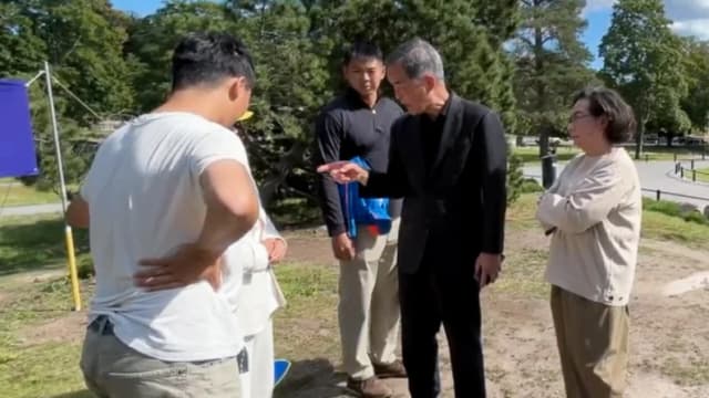 Leung Chun-ying, exjefe ejecutivo de Hong Kong, y su esposa, Regina Leung Tong Ching-yee, en un enfrentamiento con practicantes de Falun Gong en el parque Sibelius, en Helsinki, el 13 de agosto de 2025. (Cortesía de los practicantes de Falun Gong de Helsinki)