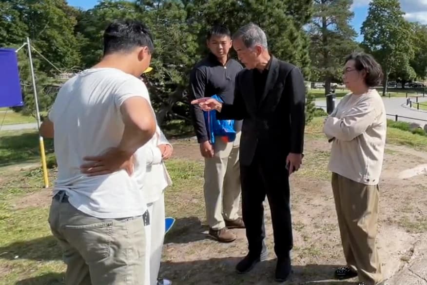 Leung Chun-ying, exjefe ejecutivo de Hong Kong, y su esposa, Regina Leung Tong Ching-yee, en un enfrentamiento con practicantes de Falun Gong en el parque Sibelius, en Helsinki, el 13 de agosto de 2025. (Cortesía de los practicantes de Falun Gong de Helsinki)