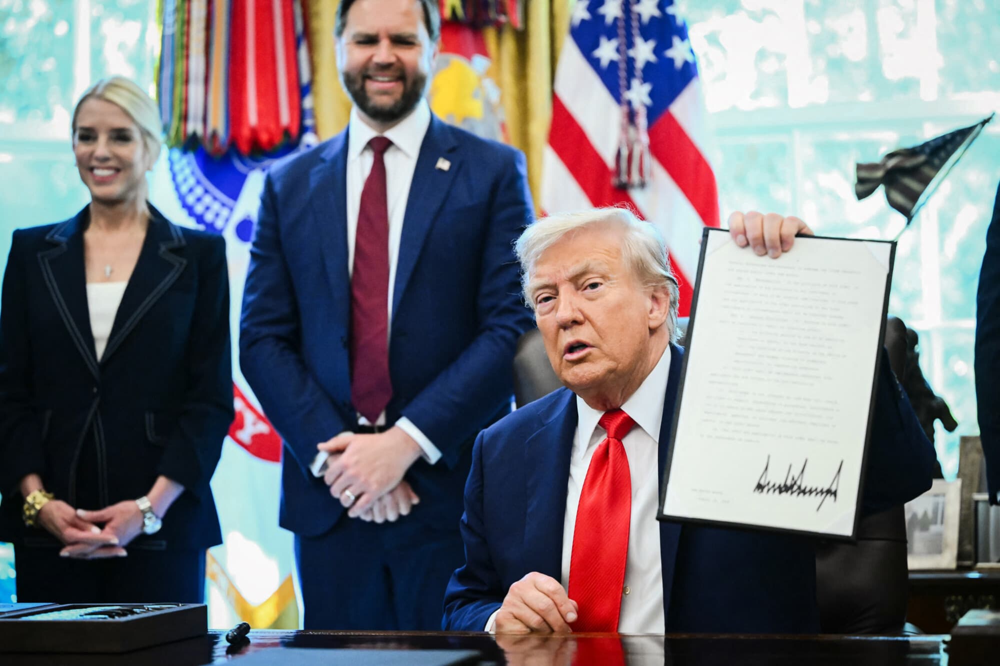 El presidente Donald Trump sostiene una orden ejecutiva firmada que tiene como objetivo poner fin a la fianza sin efectivo, en el Despacho Oval, el 25 de agosto de 2025. (Mandel Ngan/AFP a través de Getty Images).