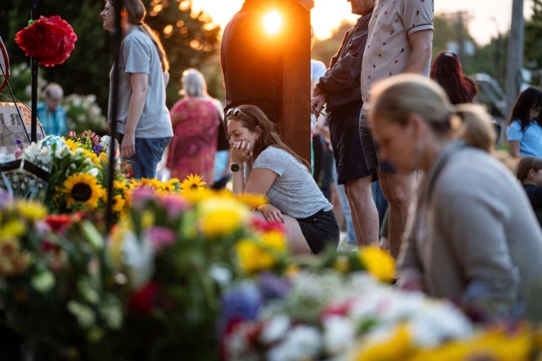 La gente se sienta en silencio para llorar la muerte de dos escolares que fueron asesinados el día anterior durante un tiroteo en la escuela católica Annunciation Catholic School de Minneapolis, el 28 de agosto de 2025. (Madalina Kilroy/The Epoch Times)
