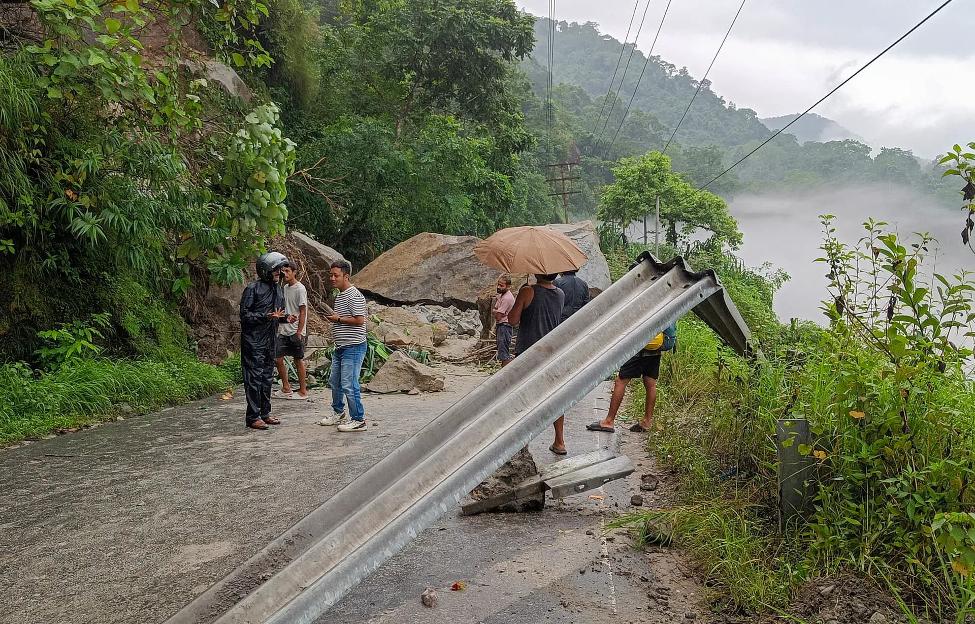Aldeanos y turistas indios cerca de los escombros después de que un deslizamiento de tierra bloqueara la Carretera Nacional 10 en la zona de Kalijhora, cerca de Sevok, a 27 kilómetros de Siliguri, India, el 30 de agosto de 2025. (Diptendu Dutta/Middle East Images/AFP vía Getty Images.)