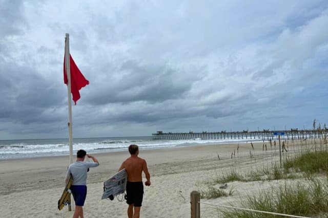 Jack Moore (izquierda) y Owen Mohr se preparan para surfear cerca del muelle pesquero de Bogue Inlet en Emerald Isle, Carolina del Norte, el 20 de agosto de 2025. T.J. Muscaro/The Epoch Times