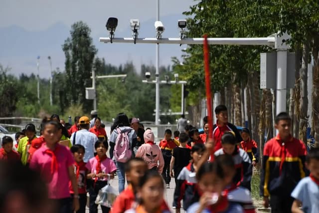Escolares caminan bajo cámaras de vigilancia en Akto, en la región occidental china de Xinjiang, el 4 de junio de 2019. (Greg Baker/AFP a través de Getty Images)
