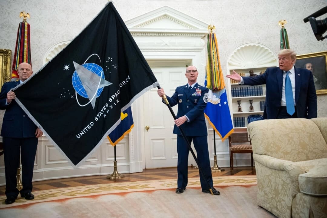 El general John "Jay" Raymond, comandante del Comando Espacial de Estados Unidos (izquierda), y el sargento mayor Roger Towberman (derecha) sostienen la bandera mientras el presidente Donald Trump hace un gesto, durante la presentación de la bandera de la Fuerza Espacial en el Despacho Oval de la Casa Blanca en Washington, el 15 de mayo de 2020. (AP/Alex Brandon, archivo)
