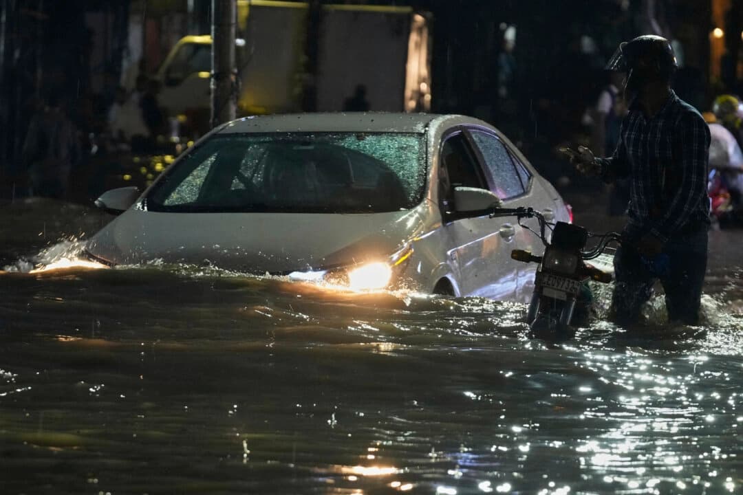 Personas en un automóvil conducen y un motociclista empuja su vehículo por una carretera inundada debido a las fuertes lluvias en Lahore, Pakistán, el 8 de septiembre de 2025. (K.M. Chaudary/AP Photo).