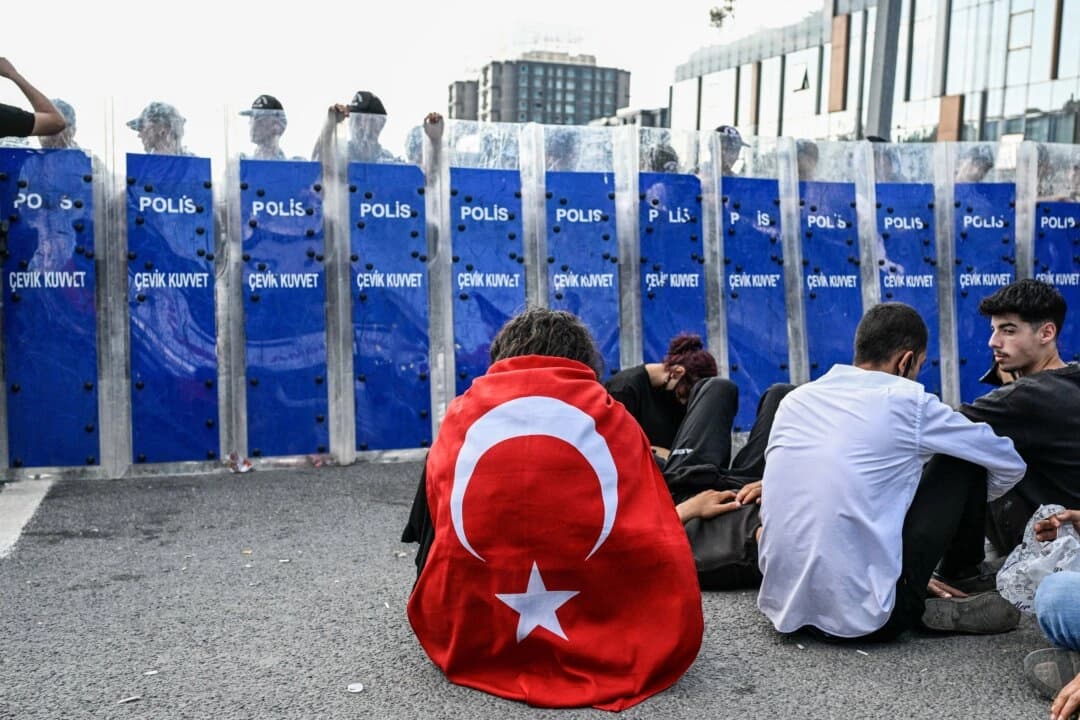 Un manifestante envuelto en la bandera turca se sienta frente a la policía antidisturbios frente a la sede del CHP, el principal partido de la oposición de Turquía, en Estambul, el 8 de septiembre de 2025. (Kemal Aslan/AFP a través de Getty Images)