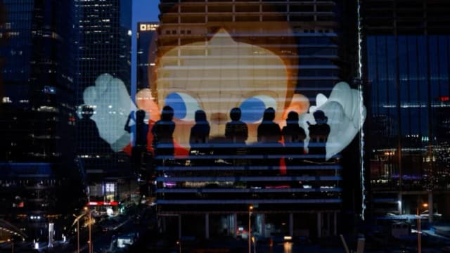 El reflejo de las siluetas de las personas se ve en un cristal de la terraza de un centro comercial con vistas al distrito comercial central de Beijing, el 11 de agosto de 2025. (Tingshu Wang/Reuters)
