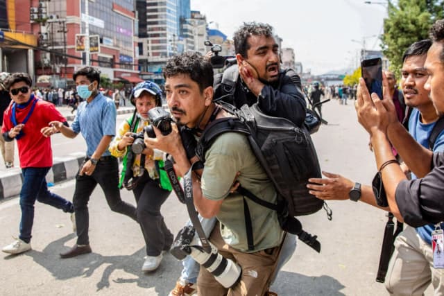 Un fotoperiodista lleva a un compañero periodista herido fuera del edificio del Parlamento en Katmandú durante una protesta contra las prohibiciones de las redes sociales, en Nepal, el 8 de septiembre de 2025. El 8 de septiembre, la policía nepalí abrió fuego y mató al menos a 17 personas cuando miles de jóvenes manifestantes salieron a las calles de Katmandú para exigir al Gobierno que levantara la prohibición de las redes sociales y combatiera la corrupción. (Prabin Ranabhat/AFP a través de Getty Images)