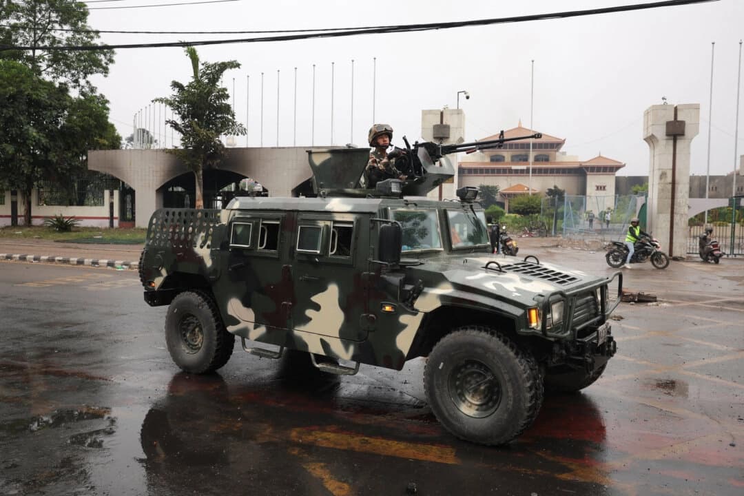 Un soldado del ejército nepalí se encuentra en un vehículo blindado que pasa por delante del Parlamento, incendiado por manifestantes en Katmandú, Nepal, el 10 de septiembre de 2025. (Adnan Abidi/Reuters)
