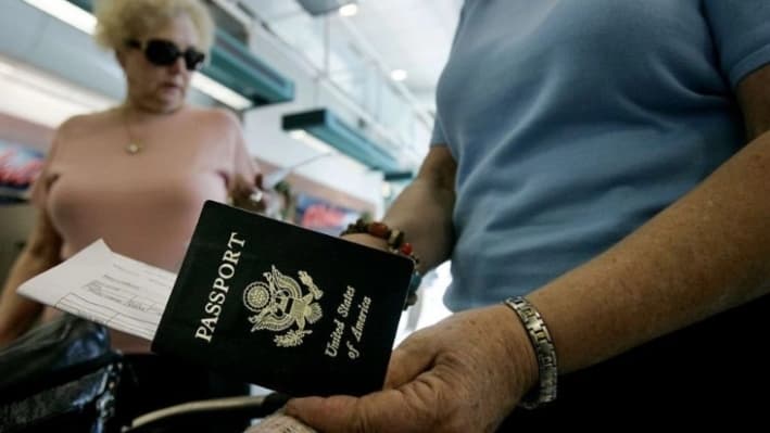 Viajeros sacan sus pasaportes antes de registrarse en el Aeropuerto Internacional de San Diego, en San Diego, California, el 8 de enero de 2006. (Sandy Huffaker/Getty Images)