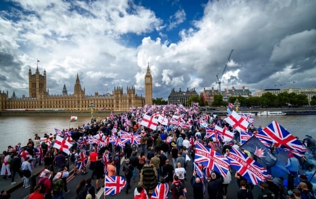 Manifestantes ondean banderas durante la manifestación "Unite The Kingdom" (Unir el Reino) en el puente de Westminster, junto a las Cámaras del Parlamento, en Londres, el 13 de septiembre de 2025. (Christopher Furlong/Getty Images)