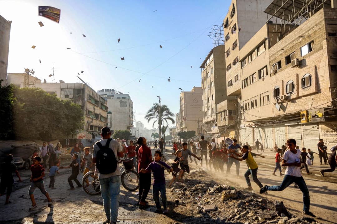 La gente observa cómo los folletos lanzados por el ejército israelí, en los que se insta a la evacuación hacia el sur, a Al-Mawasi, caen sobre la ciudad de Gaza el 9 de septiembre de 2025. (Omar Al-Qattaa/AFP a través de Getty Images)
