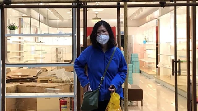 Zhang Zhan junto a un andamio frente a una tienda durante una visita a Wuhan, en la provincia de Hubei (China), el 11 de abril de 2020. (Cortesía de Melanie Wang a través de AP)