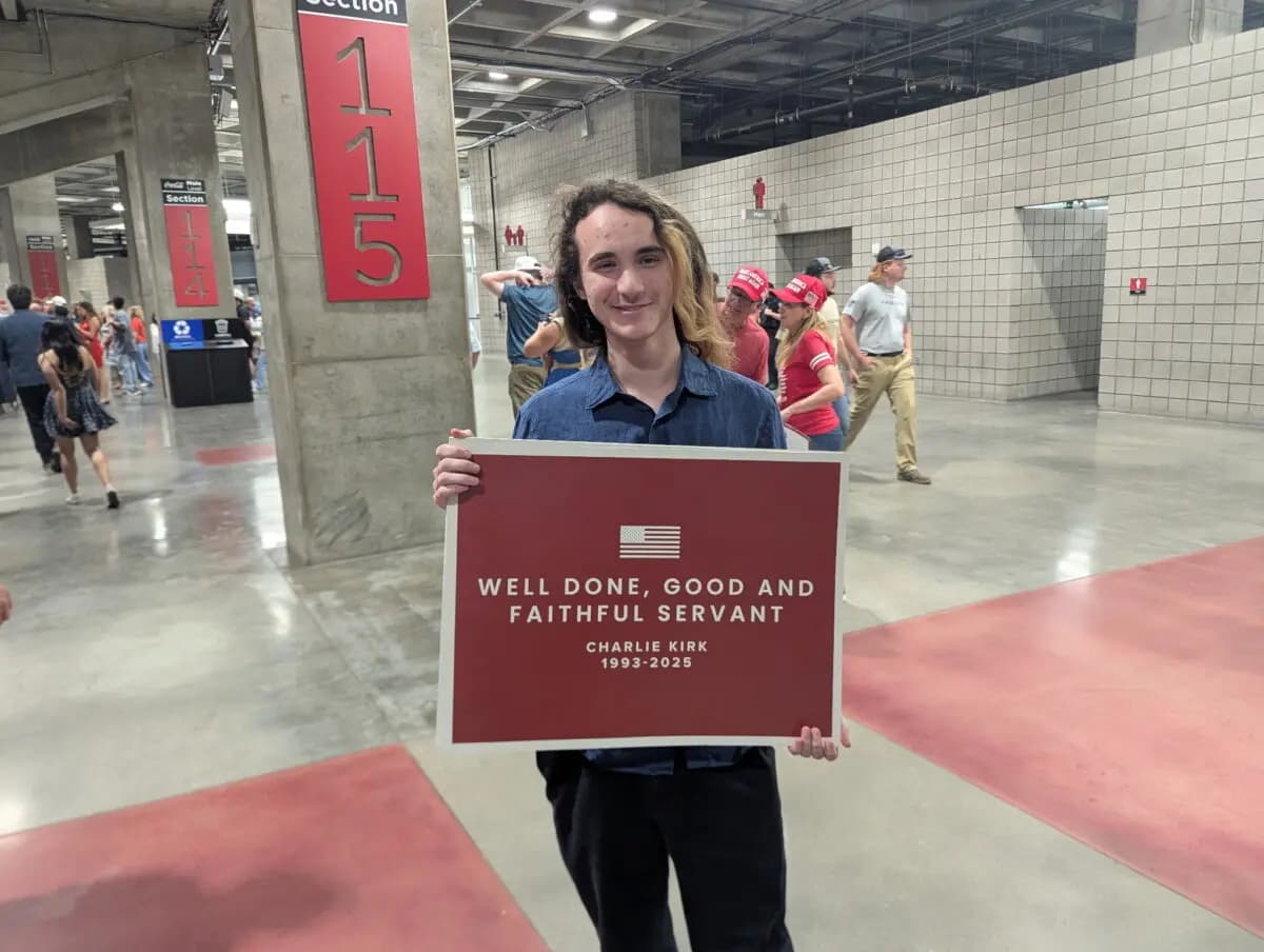 David Watz sostiene un cartel con el lema "Bien hecho, siervo bueno y fiel" en el funeral de Charlie Kirk en el State Farm Stadium de Phoenix, Arizona, el 21 de septiembre de 2025. (Ryan Morgan/The Epoch Times)