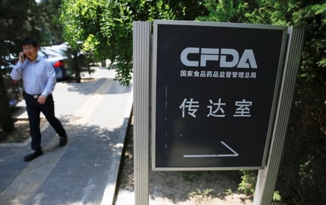 Un hombre habla por teléfono cerca de un cartel de la oficina de recepción de la Administración de Alimentos y Medicamentos de China, en Beijing, el 17 de mayo de 2016. (Damir Sagolj/Reuters)