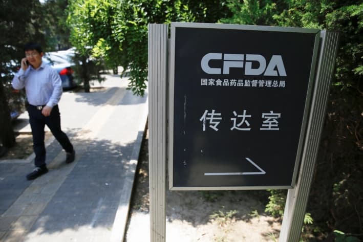 Un hombre habla por teléfono cerca de un cartel de la oficina de recepción de la Administración de Alimentos y Medicamentos de China, en Beijing, el 17 de mayo de 2016. (Damir Sagolj/Reuters)