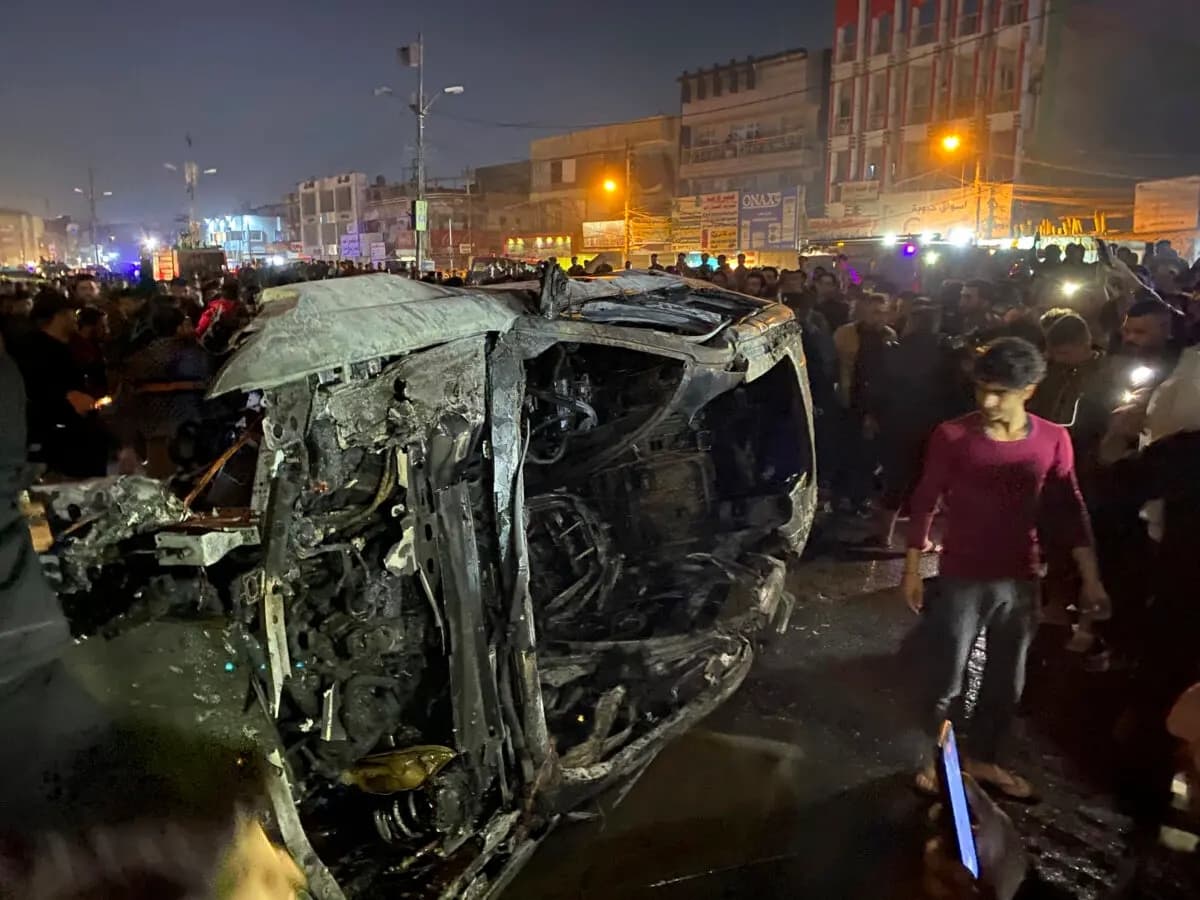 Iraquíes se reúnen en el lugar donde se encuentra un vehículo quemado tras un ataque con drones estadounidenses en Bagdad el 7 de febrero de 2024. (Hadi Mizban/AP Photo)