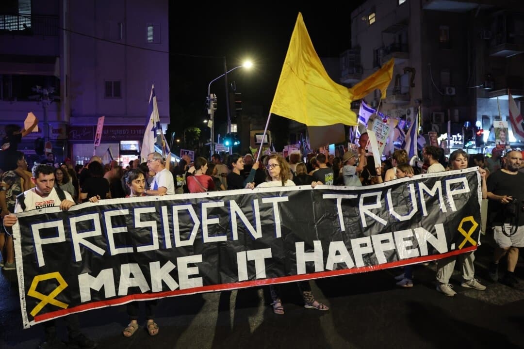 Manifestantes levantan pancartas y carteles durante una protesta contra el gobierno en la que se pide un alto el fuego y medidas para garantizar el regreso de los israelíes retenidos como rehenes en Gaza, frente al edificio del partido Likud en Tel Aviv, el 30 de septiembre de 2025. (Jack GUEZ/AFP)

