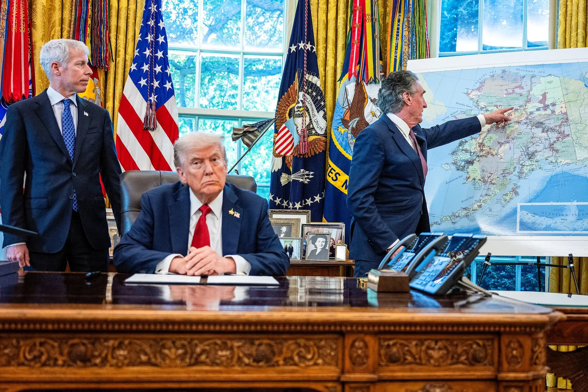 El presidente Donald Trump escucha mientras el secretario del Interior, Doug Burgum (derecha), señala un mapa de Alaska y el secretario de Energía, Chris Wright (izquierda), observa, después de que Trump firmara una orden ejecutiva para autorizar el proyecto minero Ambler Road en Alaska, en el Despacho Oval, el 6 de octubre de 2025. (Jim Watson/AFP a través de Getty Images).