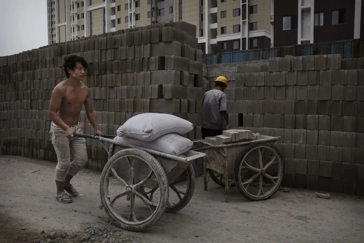 Un trabajador de la construcción chino empuja una carga de hormigón en la obra de un nuevo complejo de apartamentos en Beijing el 29 de agosto de 2014. (Kevin Frayer/Getty Images)