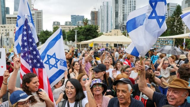 La gente ondea banderas estadounidenses e israelíes en la Plaza de los Rehenes de Tel Aviv el 9 de octubre de 2025, tras el anuncio de un nuevo acuerdo de alto el fuego en Gaza. Israel y Hamás acordaron el 9 de octubre un alto el fuego en Gaza para liberar a los rehenes que aún siguen con vida, en un paso importante hacia el fin de una guerra que ha causado la muerte de decenas de miles de personas y ha desatado una catástrofe humanitaria. (JACK GUEZ/AFP vía Getty Images)

