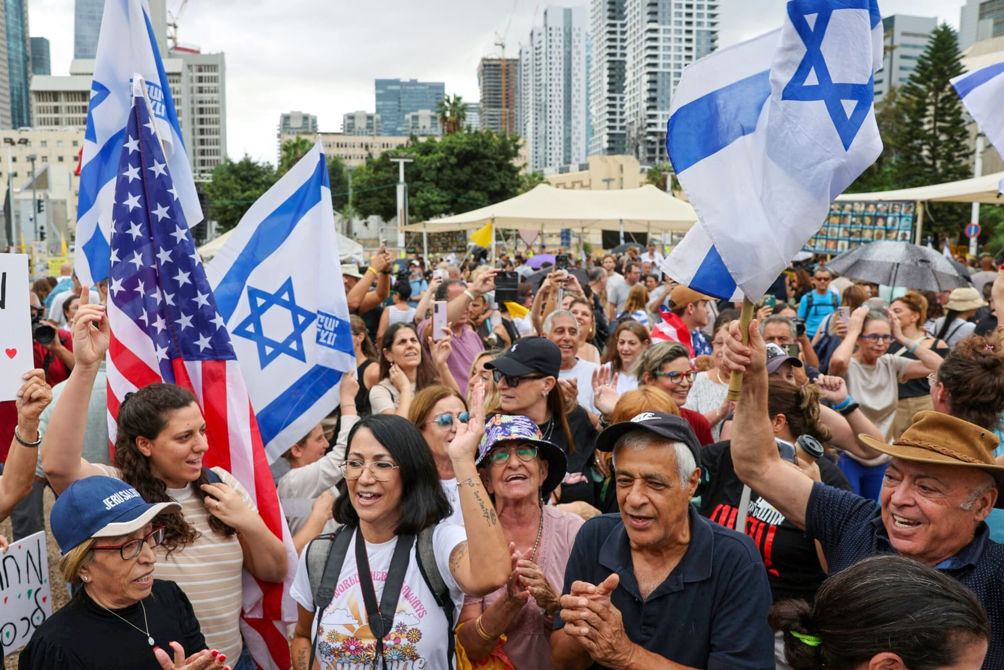 La gente ondea banderas estadounidenses e israelíes en la Plaza de los Rehenes de Tel Aviv el 9 de octubre de 2025, tras el anuncio de un nuevo acuerdo de alto el fuego en Gaza. Israel y Hamás acordaron el 9 de octubre un alto el fuego en Gaza para liberar a los rehenes que aún siguen con vida, en un paso importante hacia el fin de una guerra que ha causado la muerte de decenas de miles de personas y ha desatado una catástrofe humanitaria. (JACK GUEZ/AFP vía Getty Images)

