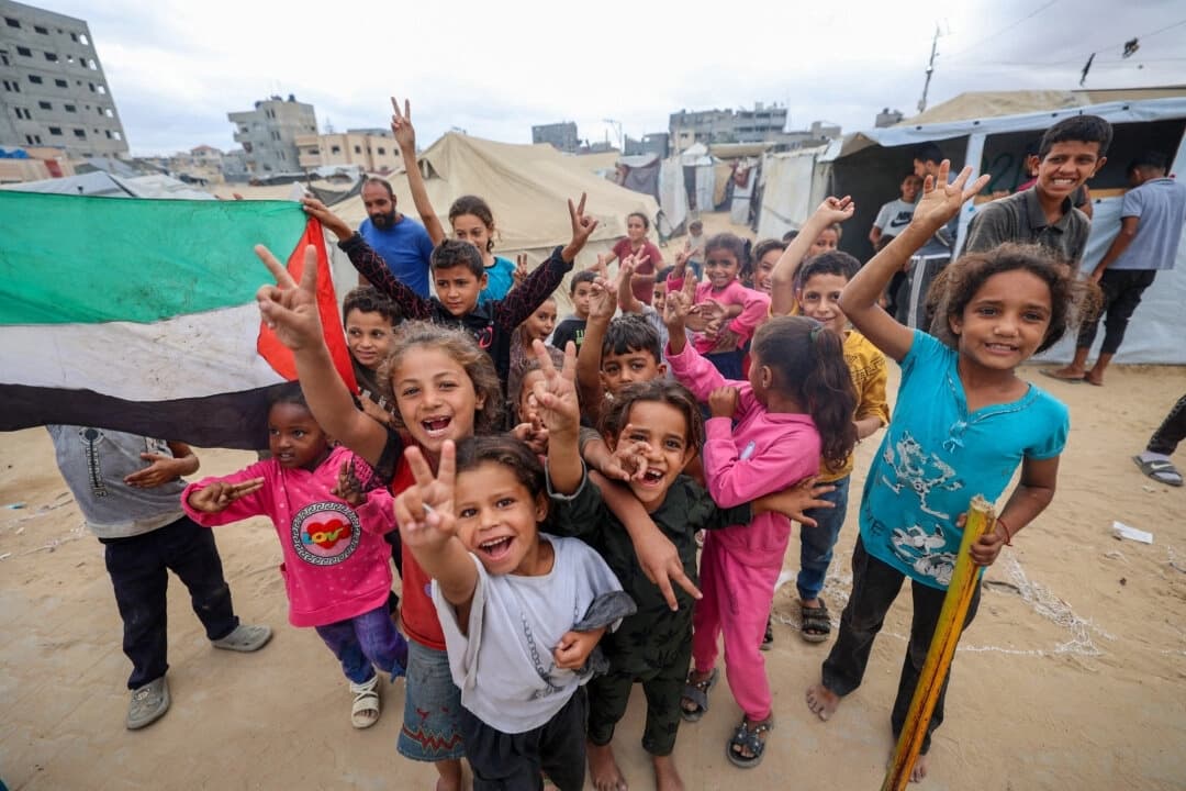Niños palestinos celebran en un campamento para personas desplazadas en Nuseirat, en el centro de la Franja de Gaza, el 9 de octubre de 2025, tras conocerse la noticia de un nuevo acuerdo de alto el fuego en Gaza. (Eyad Baba/AFP a través de Getty Images)
