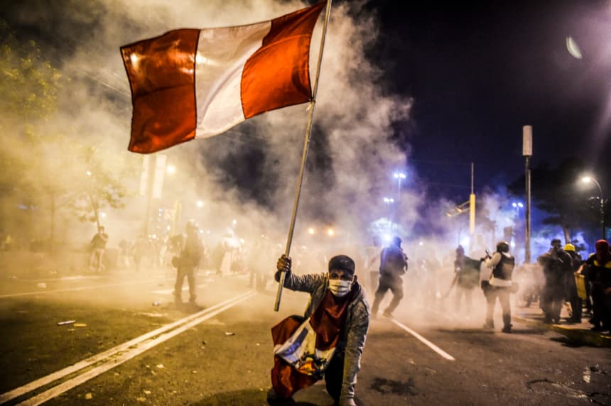 Un manifestante, simpatizante del expresidente peruano destituido Martín Vizcarra, sostiene una bandera peruana durante una protesta contra el gobierno del presidente interino Manuel Merino en Lima, el 14 de noviembre de 2020. (ERNESTO BENAVIDES/AFP via Getty Images)