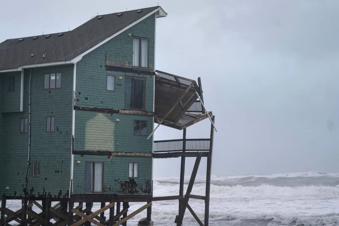 Un balcón cuelga de una casa en riesgo de derrumbe en medio de una tormenta en Buxton, Carolina del Norte, el 12 de octubre de 2025. (AP Photo/Allison Joyce)