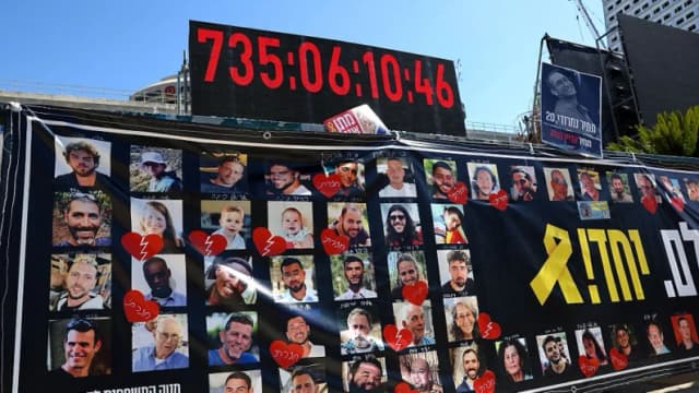 Retratos de los rehenes israelíes retenidos en la Franja de Gaza desde los ataques del 7 de octubre de 2023 se exhiben bajo un reloj digital que muestra los días, horas y minutos que llevan cautivos, frente al Museo de Arte de Tel Aviv, conocido como "Plaza de los Rehenes", en Tel Aviv, Israel, el 11 de octubre de 2025. (Jack Guez/AFP a través de Getty Images).