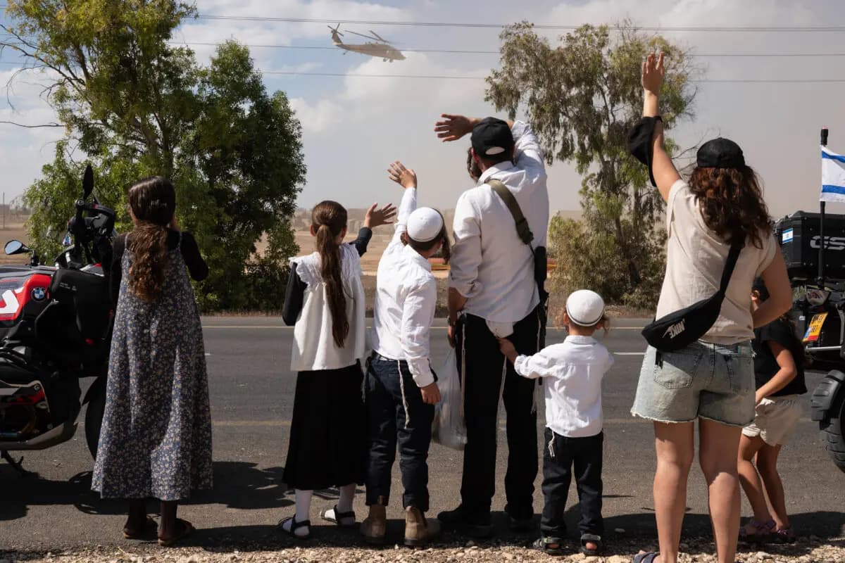 <em>Israelíes se reúnen con banderas nacionales frente a la base militar de Reim, cerca de la frontera con Gaza, en el sur de Israel, para dar la bienvenida a los rehenes que estaban a punto de llegar tras su liberación por Hamás de la Franja de Gaza el 13 de octubre de 2025. (MAYA LEVIN/AFP vía Getty Images)</em>
