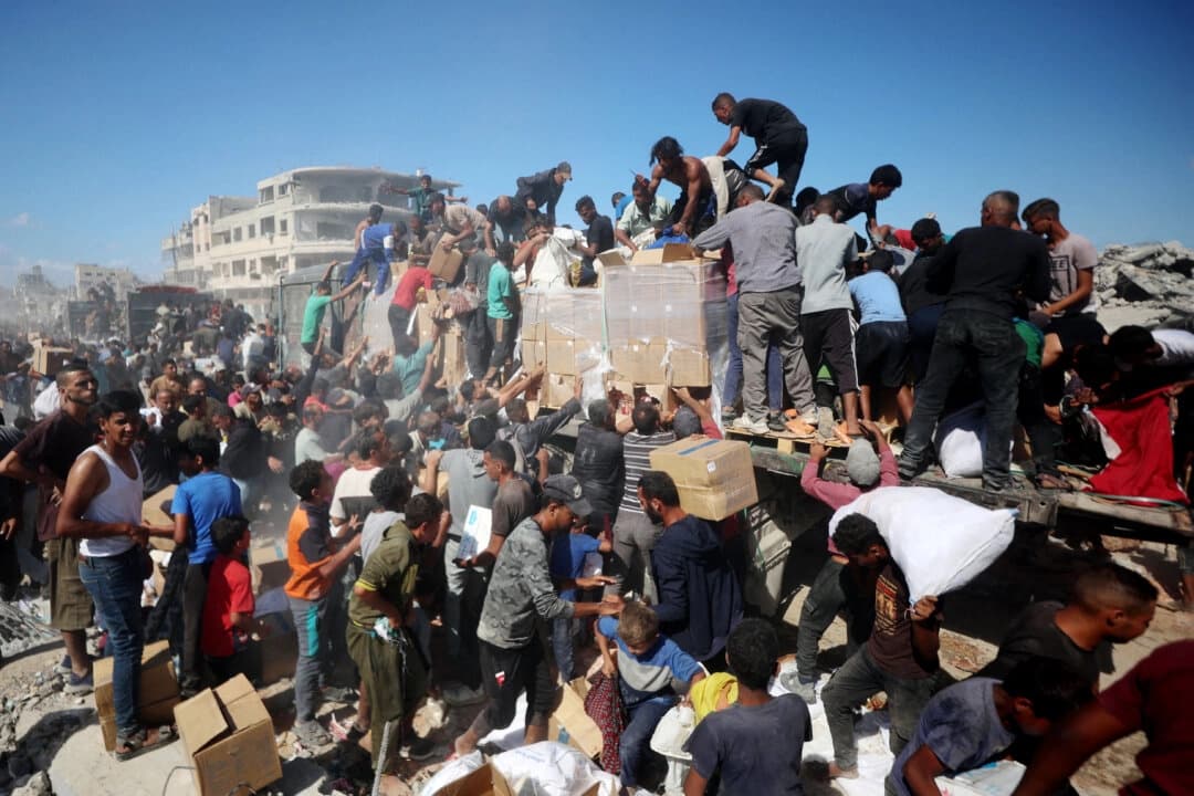 Palestinos recogen paquetes de ayuda de camiones que ingresaron desde el cruce de Karem Abu Salem, en Khan Yunis, en el sur de la Franja de Gaza, el 12 de octubre de 2025. (Omar Al-Qattaa/AFP vía Getty Images)