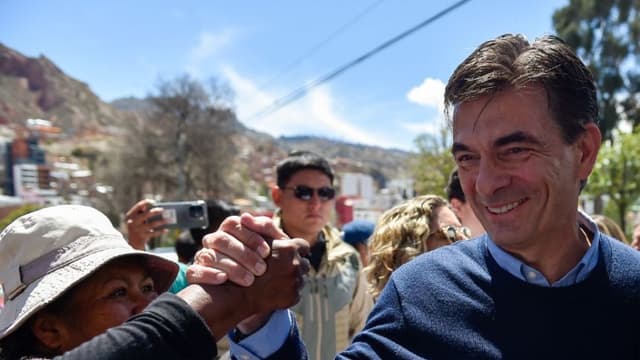 El candidato presidencial de Bolivia por el Partido Demócrata Cristiano (PDC), Rodrigo Paz, saluda a un simpatizante al llegar a un centro de votación mientras acompaña a su hija Catalina (fuera de cuadro) a votar durante la segunda vuelta de las elecciones presidenciales en La Paz el 19 de octubre de 2025.  (Foto de JORGE BERNAL/AFP vía Getty Images)