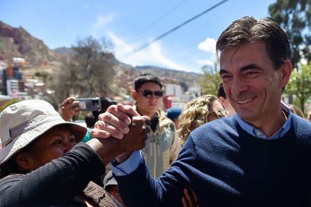 El candidato presidencial de Bolivia por el Partido Demócrata Cristiano (PDC), Rodrigo Paz, saluda a un simpatizante al llegar a un centro de votación mientras acompaña a su hija Catalina (fuera de cuadro) a votar durante la segunda vuelta de las elecciones presidenciales en La Paz el 19 de octubre de 2025.  (Foto de JORGE BERNAL/AFP vía Getty Images)