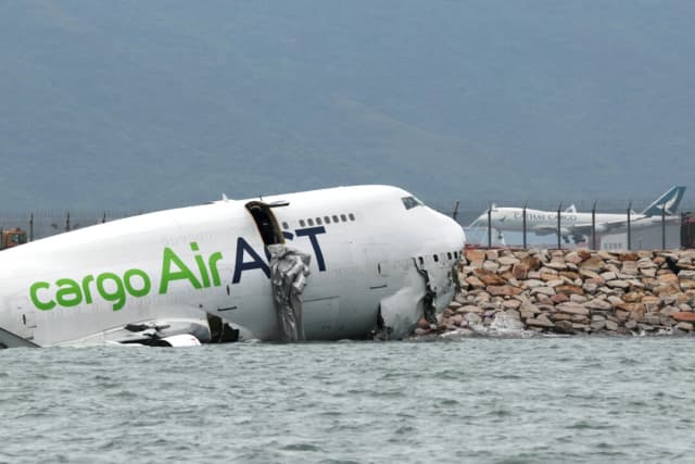 Un avión de carga yace parcialmente en el mar tras salirse de la pista durante el aterrizaje en el Aeropuerto Internacional de Hong Kong, el 20 de octubre de 2025. (Tyrone Siu/Reuters)